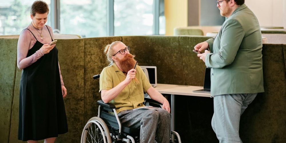 Photo représentant une personne en fauteuil roulant et un personne debout discutant ensemble.