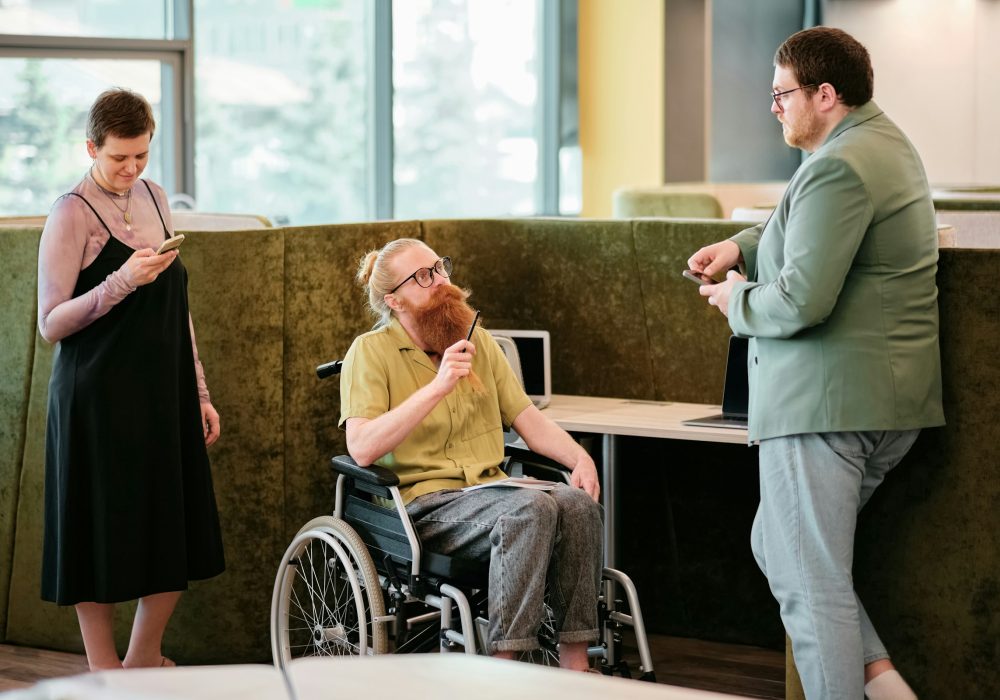Photo représentant une personne en fauteuil roulant et un personne debout discutant ensemble.