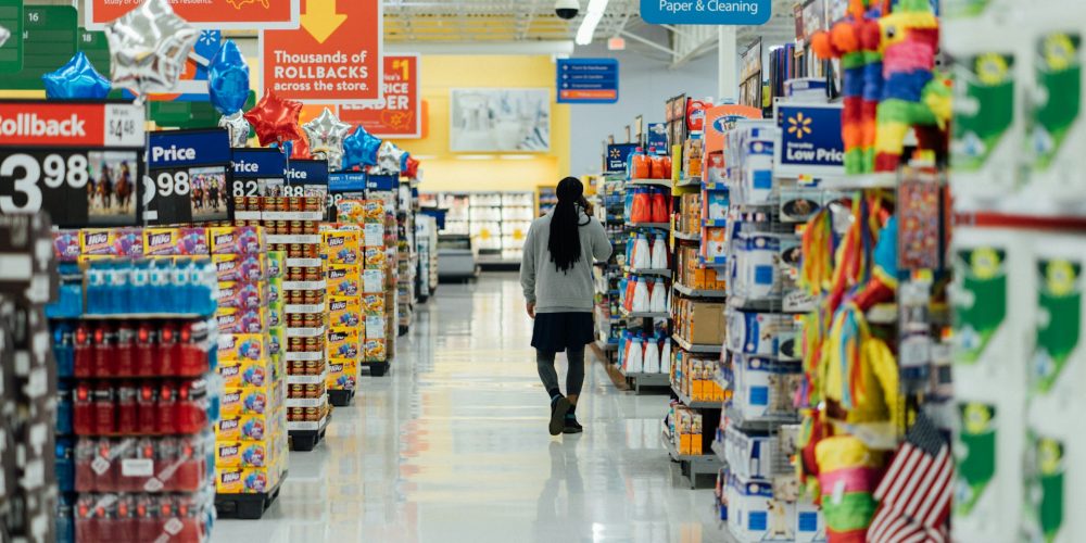 Photo qui illustre l'article : Mise en demeure des entreprises Auchan, Carrefour, E. Leclerc et Picard Surgelés. La photographie représente une personne marchant dans les rayons d'un supermarché.