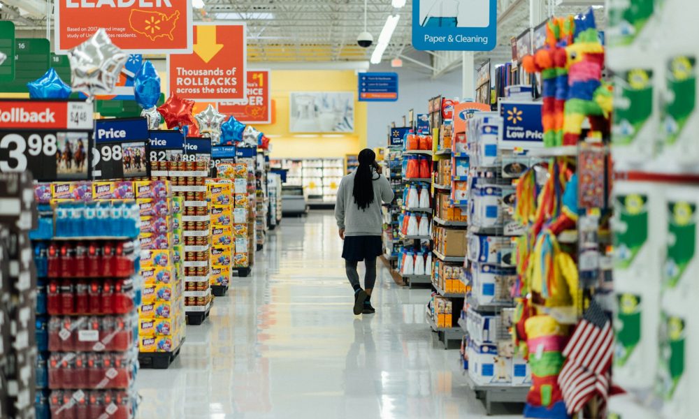 Photo qui illustre l'article : Mise en demeure des entreprises Auchan, Carrefour, E. Leclerc et Picard Surgelés. La photographie représente une personne marchant dans les rayons d'un supermarché.