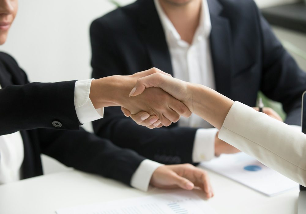Photo qui représente deux personnes se serrant la main dans un bureau.
